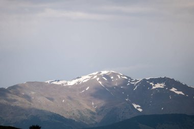 Güzel mavi bulutlu gökyüzü olan karlı bir dağın dikey görüntüsü.
