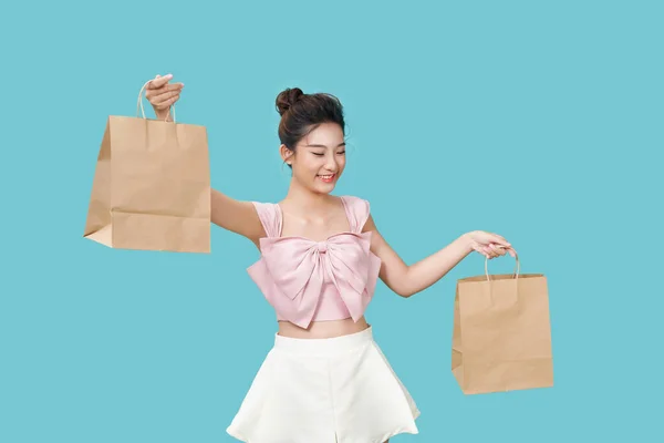 一个年轻漂亮的姑娘在青色的背景上炫耀她的棕色大纸袋 — 图库照片