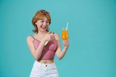 Heyecanlı genç bayan, turkuaz bir yaz partisinin arka planında eğleniyor ve gülüyor.