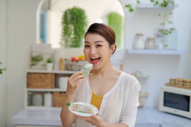 Asian woman eating tasty traditional spring rolls
