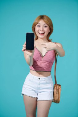 Şirin Asyalı kadın reklam ya da uygulama reklamı için boş ekran akıllı telefonu sunuyor.