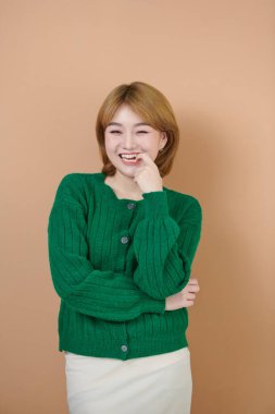 Hoş görünümlü genç bir bayan manken sağlıklı bir teni var, parmağını ısırıyor, bej arka planda utanıyor.. 