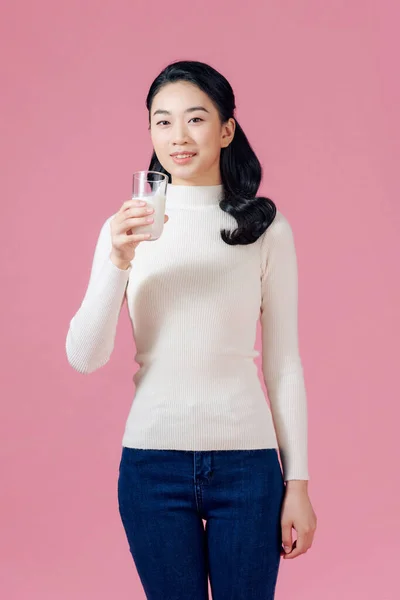 여성은 분홍색 배경에 유리에서 우유를 마시고 — 스톡 사진