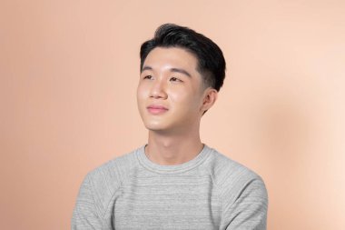 Bej arka planda izole edilmiş gülümseyen yakışıklı bir adamın portresi.