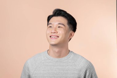 Bej arka planda izole edilmiş gülümseyen yakışıklı bir adamın portresi.