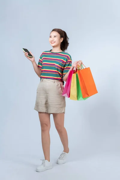 モバイルアプリで購入を楽しむ女性は 灰色の背景に立って — ストック写真