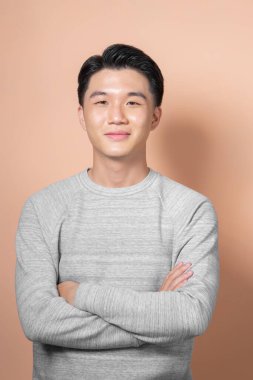 Çekici, neşeli, tecrübeli, zeki bir adamın portresi bej arka planda izole edilmiş kollarını kavuşturdu.