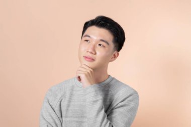 Eli çenesinde Asyalı genç bir adam soru soruyor, düşünceli bir yüz ifadesi var..