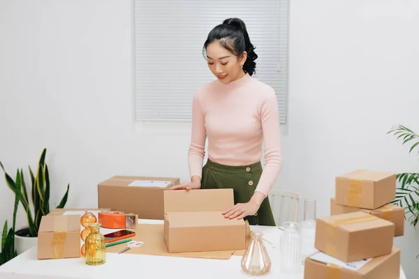 Women packing package with her products that she selling online