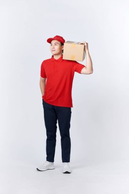 Postanede çalışıyorum. Kırmızı üniformalı kurye büyük bir paket tutuyor, boş yer, stüdyo fotoğrafı.