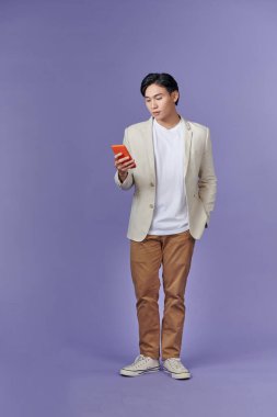 Yakışıklı bir adamın telefon bağımlısı olarak SMS yazarken tam boy fotoğrafı.