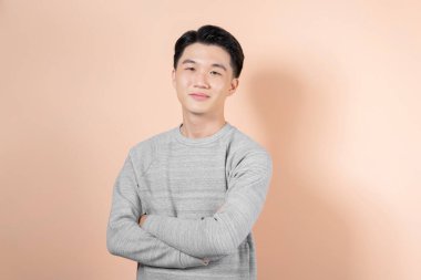 Young smiling asian man looking at camera isolated on beige background