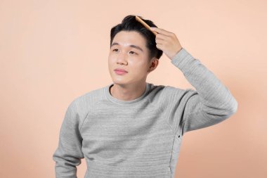 Young man combing his hair with a wooden comb.