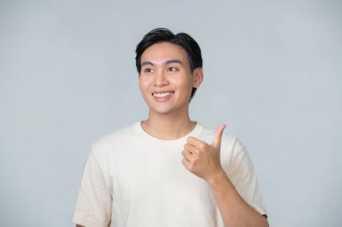 Nice smile friendly Asian man in white t-shirt giving thumbs up