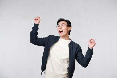 Başarıyı kutlayan genç bir adamın portresi beyaz arka planda izole edilmiş.