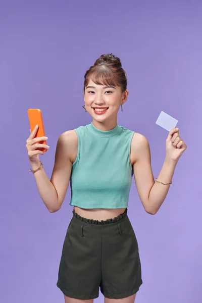 stock image Happy young woman using mobile phone and credit card.