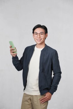 Smart casual asian man using smartphone in studio background
