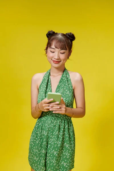 Piękna Azjatka Trzyma Smartfona Uśmiecha Się Jasnożółtym Tle — Zdjęcie stockowe