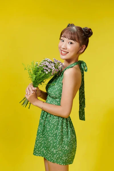 素敵な若いアジアの女性の写真は黄色の背景に隔離された夏の服を着て花を保持 — ストック写真