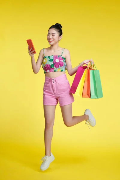 全身上下都是快乐的年轻迷人的购物狂女人 她提着购物袋 拿着手机 — 图库照片