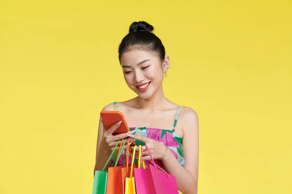 Šťastný Mladý Asijské Žena Slaví Mobilním Telefonem Držení Nákupních Tašek — Stock fotografie