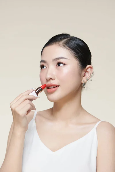 Hermosa Sonriente Asiática Mujer Sosteniendo Rojo Lápiz Labial Aislado Beige —  Fotos de Stock