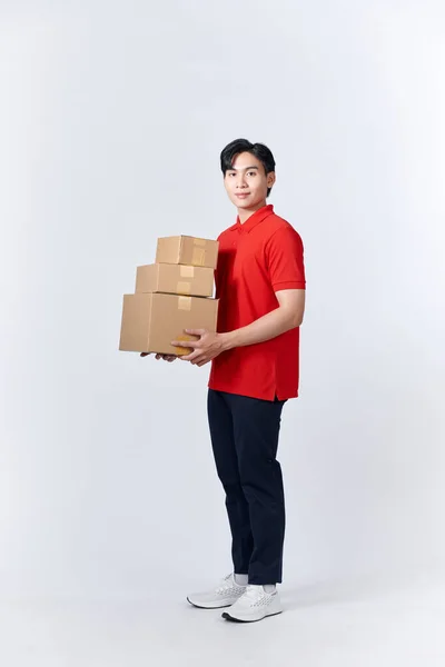 身穿红衫的年轻人 拿着三个纸盒在白墙上 — 图库照片