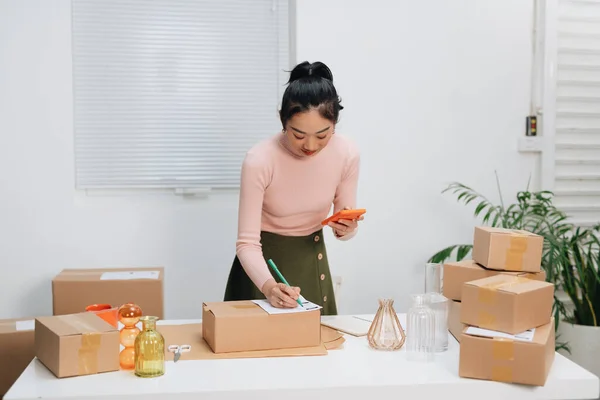 Closeup view of female online store packing package post shipping boxes preparing delivery