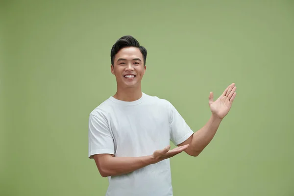Feliz Joven Asiático Hombre Mostrando Algo Imaginario Sobre Verde Fondo —  Fotos de Stock