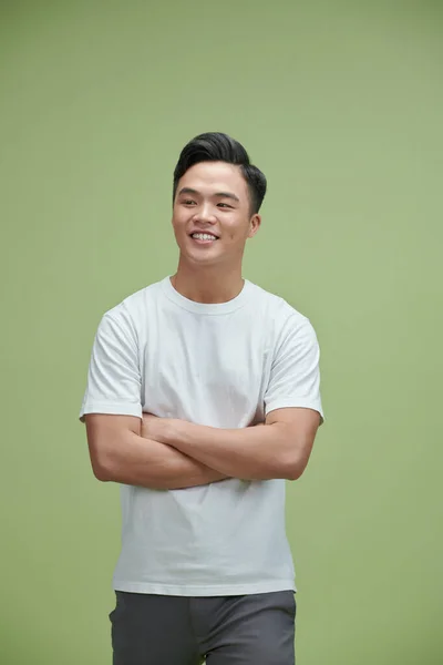 Yeşil Stüdyoda Kollarını Kavuşturmuş Gülümseyen Asyalı Genç Bir Adam Izole — Stok fotoğraf
