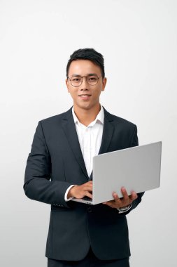 Resmi takım elbiseli gülümseyen genç iş adamının portresi açık bir laptop tutuyor. 