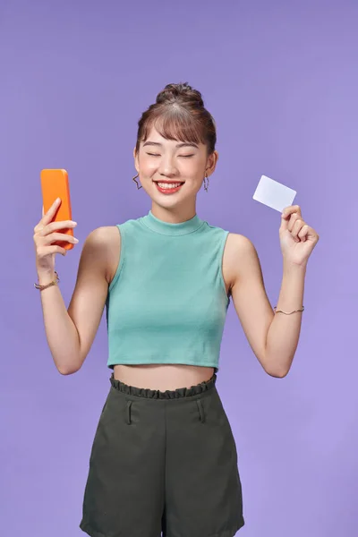 Щаслива Азіатська Жінка Тримає Кредитну Картку Смартфон Кольоровому Фоні — стокове фото