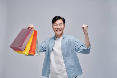 Alışveriş torbalarını gösteren ve indirimlerden zevk alan heyecanlı bir adam.,