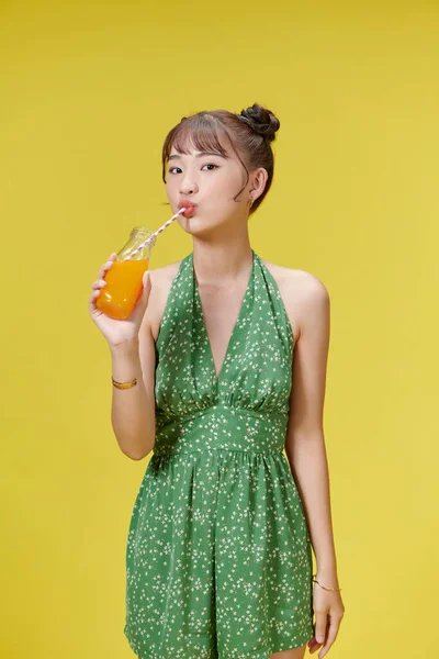 Excitada Mulher Asiática Bebendo Suco Laranja Vidro Fundo Amarelo — Fotografia de Stock