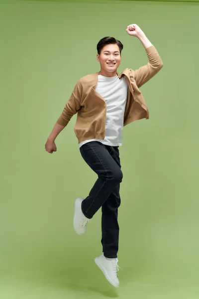 Mutlu Asyalı Genç Adam Yeşil Stüdyo Arka Planında Izole Atlıyor — Stok fotoğraf