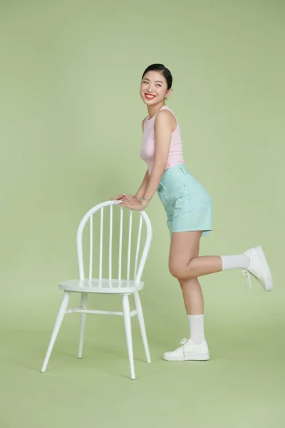 Sorrindo Asiático Mulher Topo Posando Perto Moderna Cadeira Isolada Verde — Fotografia de Stock