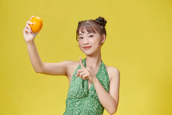 Atrakcyjna Pogodna Kobieta Demonstrująca Świeżą Zdrową Pomarańczę Odizolowaną Jasnożółtym Tle — Zdjęcie stockowe