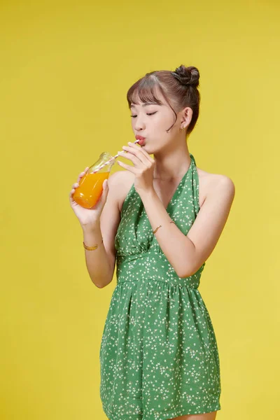 Portret Uroczej Dziewczyny Pijącej Sok Pomarańczowy Szklanki Nad Żółtym — Zdjęcie stockowe