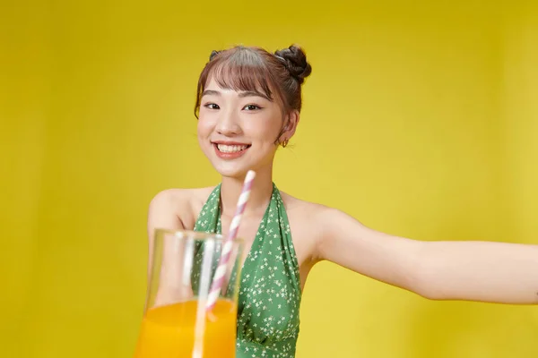愉快的亚洲女人 站在黄色一边 一边用稻草喝橙汁 — 图库照片