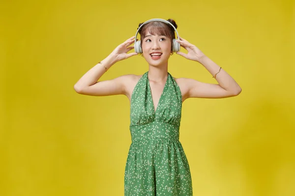 Szczęśliwa Azjatka Nosząca Słuchawki Słuchające Muzyki Smartfona Żółtym Tłem — Zdjęcie stockowe