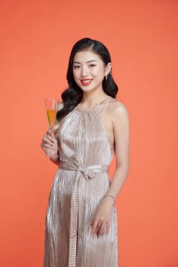 Güzel, çekici bir kadın, elinde şampanya kadehiyle şık bir elbise giyer.