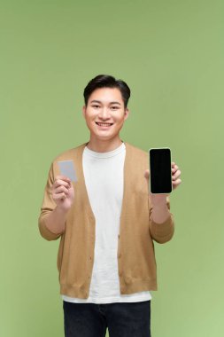Elinde boş cep telefonu tutan ve kredi kartı gösteren gülümseyen genç bir adam.