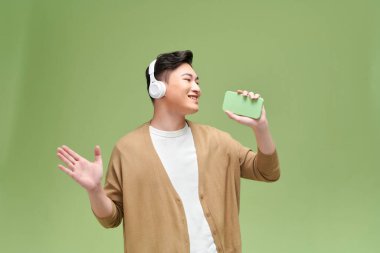 Genç yakışıklı adam en sevdiği şarkıyı söylüyor, akıllı telefonu mikrofon olarak kullanıyor., 