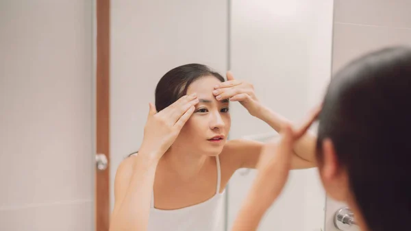 鏡面反射の美しさ 鏡を見ながら顔に触れる美しい女性 — ストック写真