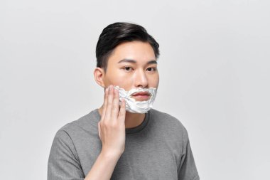 Traş olmadan önce tıraş köpüğü kullanan yakışıklı bir adam. 