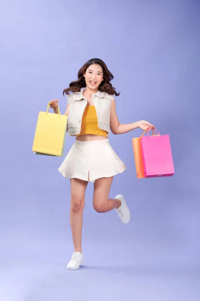 ショッピングバッグや笑顔を運ぶカジュアル服の美しい若い女性の完全な長さ — ストック写真