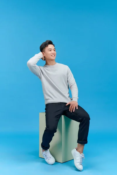 Mutlu Yakışıklı Genç Adam Mavi Üzerinde Tek Başına Otururken Kameraya — Stok fotoğraf