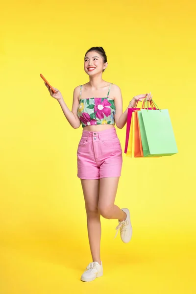 一个拿着购物袋用手机的年轻女子的画像 — 图库照片