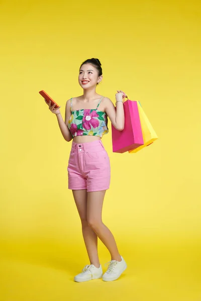 Ung Glad Glad Kvinna Som Håller Shoppingväskor Isolerade Över Gul — Stockfoto