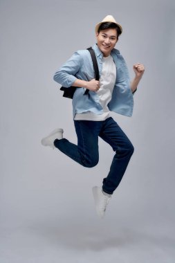 Beyaz arka planda sırtüstü yüzen ve zıplayan Asyalı genç turist.